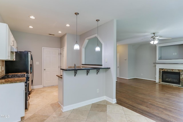 1310 Southgate Dr, Raleigh, NC 27610 - kitchen with a breakfast bar area, gas stove, white cabinets, recessed lighting, and a ceiling fan