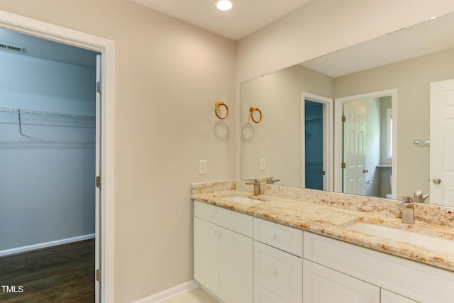 1310 Southgate Dr, Raleigh, NC 27610 - full bathroom featuring double vanity, wood finished floors, a spacious closet, baseboards, and recessed lighting
