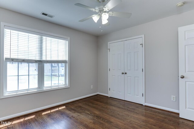 1310 Southgate Dr, Raleigh, NC 27610 - unfurnished bedroom featuring multiple windows, dark wood finished floors, baseboards, and a closet