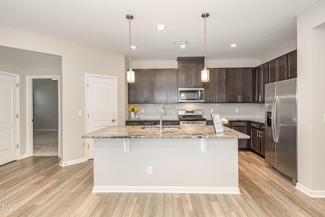 157 Willow Grove Ln, Fuquay Varina, NC 27526 - kitchen featuring stainless steel appliances, a sink, dark brown cabinets, light stone counters, and tasteful backsplash