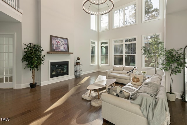 1475 Sierra Glen Cir, Apex, NC 27502 - living area featuring a high ceiling, wood-type flooring, a glass covered fireplace, baseboards, and a chandelier