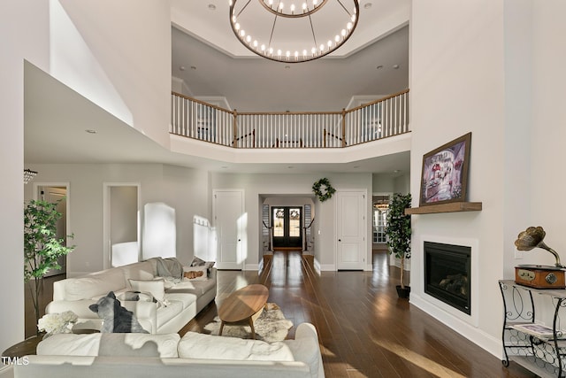 1475 Sierra Glen Cir, Apex, NC 27502 - living room with a chandelier, wood-type flooring, a towering ceiling, a glass covered fireplace, and baseboards