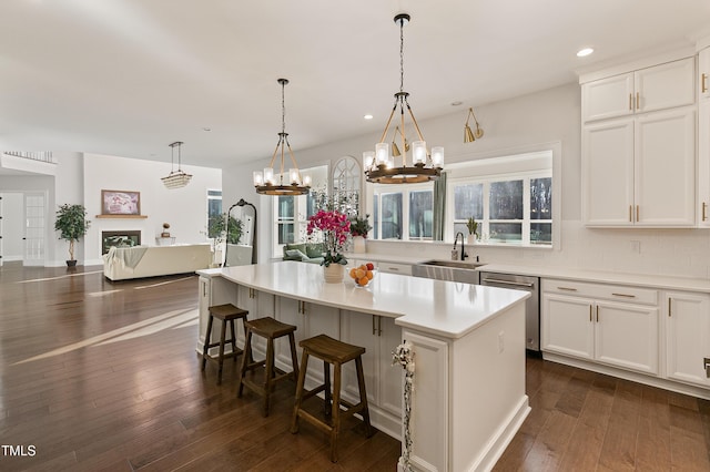 1475 Sierra Glen Cir, Apex, NC 27502 - kitchen with stainless steel dishwasher, a sink, a chandelier, light countertops, and white cabinetry