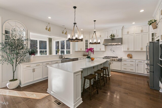 1475 Sierra Glen Cir, Apex, NC 27502 - kitchen with under cabinet range hood, stainless steel gas cooktop, a chandelier, white cabinets, and a sink