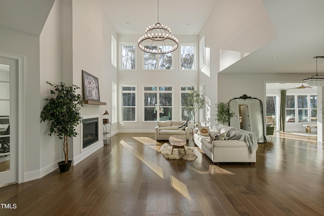 1475 Sierra Glen Cir, Apex, NC 27502 - living area with a high ceiling, a glass covered fireplace, a chandelier, dark wood-style floors, and baseboards