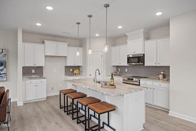433 Old Fashioned Way, Lillington, NC 27546 - kitchen with appliances with stainless steel finishes, tasteful backsplash, white cabinetry, light wood-style flooring, and a kitchen breakfast bar