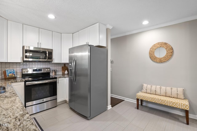 821 Stoneybrook Dr, Sanford, NC 27330 - kitchen featuring appliances with stainless steel finishes, white cabinetry, light stone counters, decorative backsplash, and ornamental molding