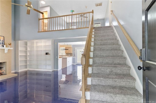 1266 Exeter Ln, Fayetteville, NC 28314 - stairway with a towering ceiling, a ceiling fan, a fireplace, and baseboards
