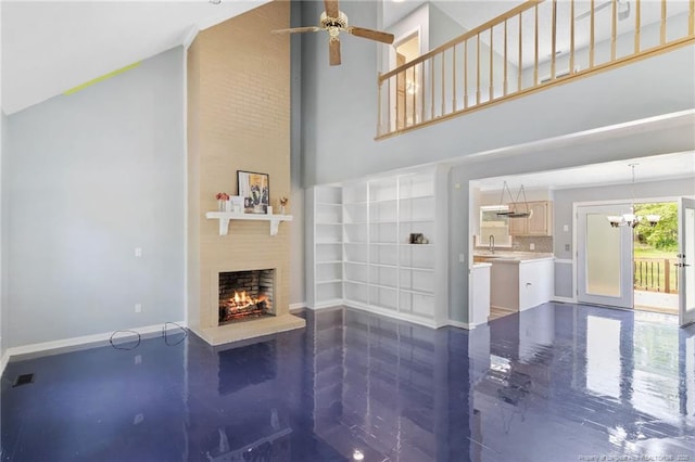 1266 Exeter Ln, Fayetteville, NC 28314 - unfurnished living room with a towering ceiling, a large fireplace, a ceiling fan, baseboards, and a chandelier