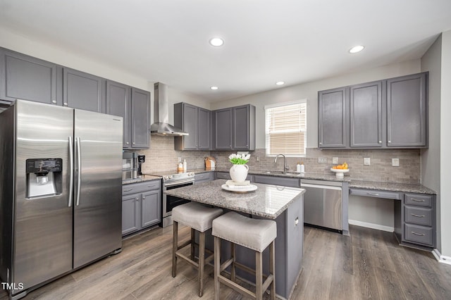 1211 Whispering Oak Ln, Durham, NC 27704 - kitchen with stainless steel appliances, wall chimney range hood, a sink, a breakfast bar, and dark wood finished floors