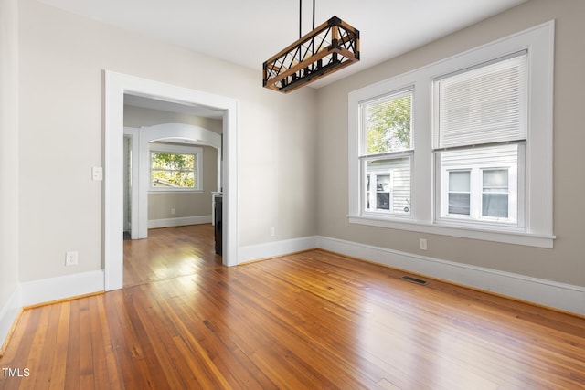 409 N Hyde Park Ave, Durham, NC 27703 - spare room featuring arched walkways, baseboards, and hardwood / wood-style floors