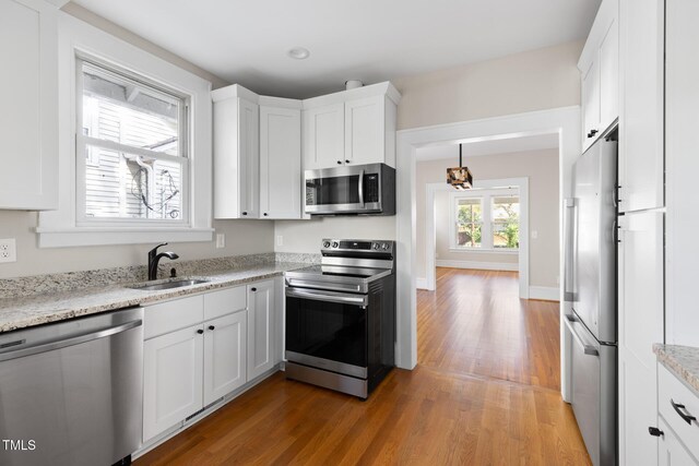 409 N Hyde Park Ave, Durham, NC 27703 - kitchen featuring appliances with stainless steel finishes, a sink, light wood-style floors, and white cabinetry