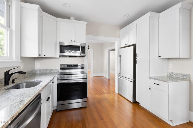 409 N Hyde Park Ave, Durham, NC 27703 - kitchen with stainless steel appliances, a sink, white cabinets, wood finished floors, and light stone counters