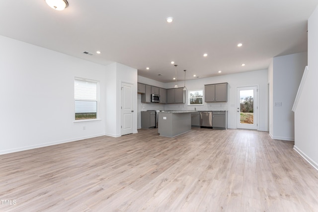 136 Bruce Dr, Dunn, NC 28334 - kitchen with appliances with stainless steel finishes, gray cabinets, open floor plan, a kitchen island, and light wood-style flooring