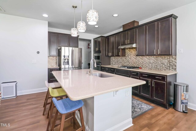 1021 Benay Rd, Morrisville, NC 27560 - kitchen featuring appliances with stainless steel finishes, a sink, under cabinet range hood, a kitchen bar, and decorative backsplash