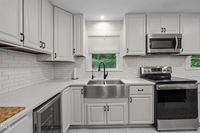 1785 Mitchells Chapel Rd, Pittsboro, NC 27312 - kitchen with appliances with stainless steel finishes, wine cooler, a sink, white cabinets, and light stone counters