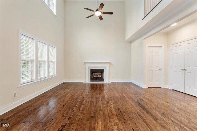 1817 Foxbrook Dr, Raleigh, NC 27603 - unfurnished living room featuring a high ceiling, ceiling fan, dark wood-style floors, a high end fireplace, and baseboards