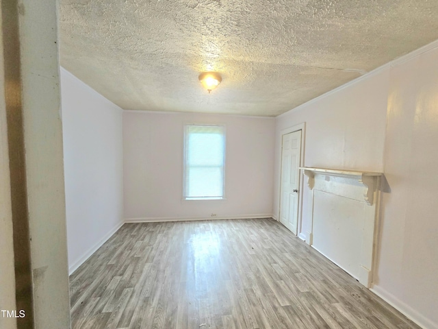 1109 N George St, Goldsboro, NC 27530 - unfurnished living room featuring a textured ceiling, light wood finished floors, baseboards, and crown molding