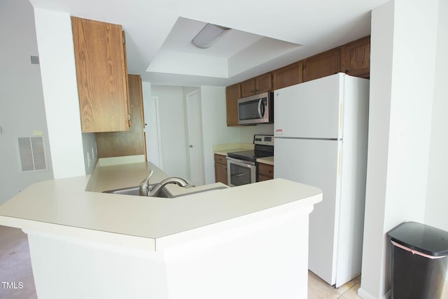115 Abingdon Ct Unit 2B, Cary, NC 27513 - kitchen featuring appliances with stainless steel finishes, a raised ceiling, a peninsula, and light countertops