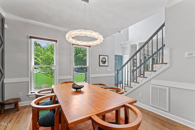 4408 Queenstown Ct, Raleigh, NC 27612 - dining space with light wood-style floors, a chandelier, crown molding, stairs, and baseboards