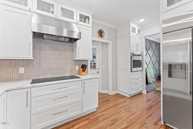 4408 Queenstown Ct, Raleigh, NC 27612 - kitchen with appliances with stainless steel finishes, under cabinet range hood, ornamental molding, backsplash, and white cabinets