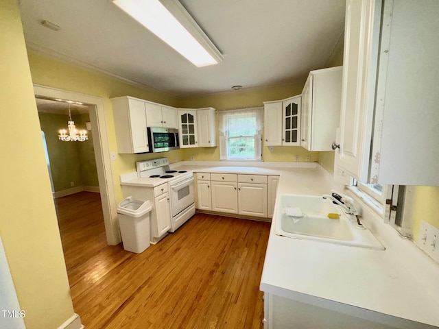 1609 Cypress Dr, Henderson, NC 27536 - kitchen with white electric stove, stainless steel microwave, a sink, light wood finished floors, and a chandelier