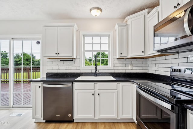 128 Newton Ct, Raeford, NC 28376 - kitchen with appliances with stainless steel finishes, a sink, decorative backsplash, dark countertops, and a textured ceiling