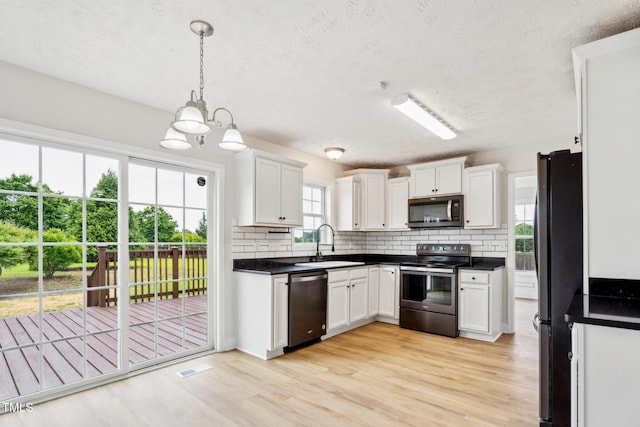 128 Newton Ct, Raeford, NC 28376 - kitchen with stainless steel appliances, a sink, dark countertops, light wood finished floors, and a textured ceiling