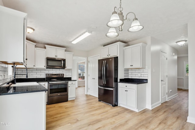 128 Newton Ct, Raeford, NC 28376 - kitchen with appliances with stainless steel finishes, dark countertops, decorative backsplash, light wood-style floors, and white cabinetry