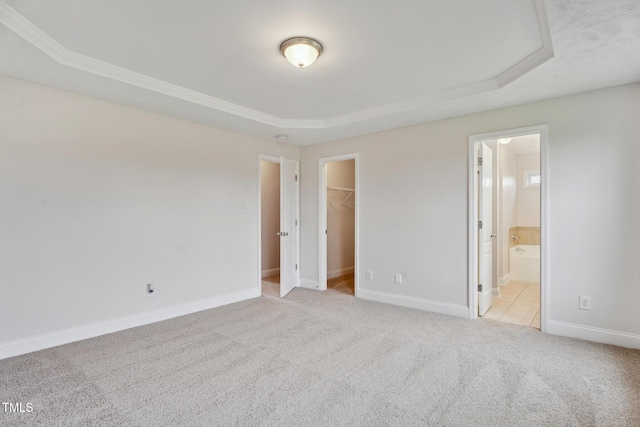 128 Newton Ct, Raeford, NC 28376 - unfurnished bedroom with a tray ceiling, light carpet, a walk in closet, baseboards, and a closet