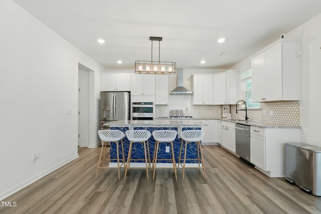 187 Harpers Landing Rd, Garner, NC 27529 - kitchen with wall chimney range hood, stainless steel appliances, a sink, light wood-style flooring, and white cabinets