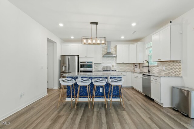 187 Harpers Landing Rd, Garner, NC 27529 - kitchen with wall chimney range hood, stainless steel appliances, a sink, light wood-style flooring, and white cabinets