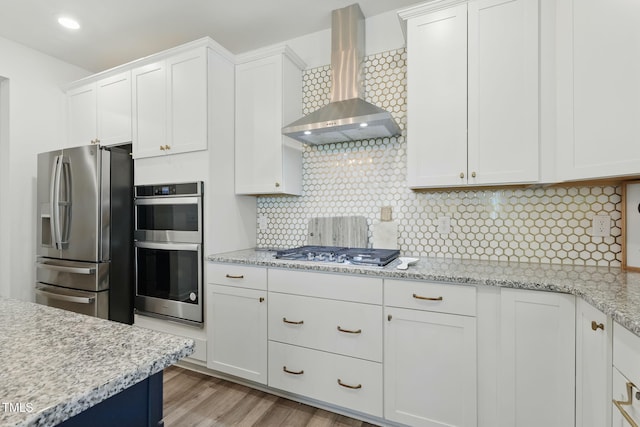 187 Harpers Landing Rd, Garner, NC 27529 - kitchen with wall chimney exhaust hood, appliances with stainless steel finishes, white cabinets, backsplash, and light wood-type flooring