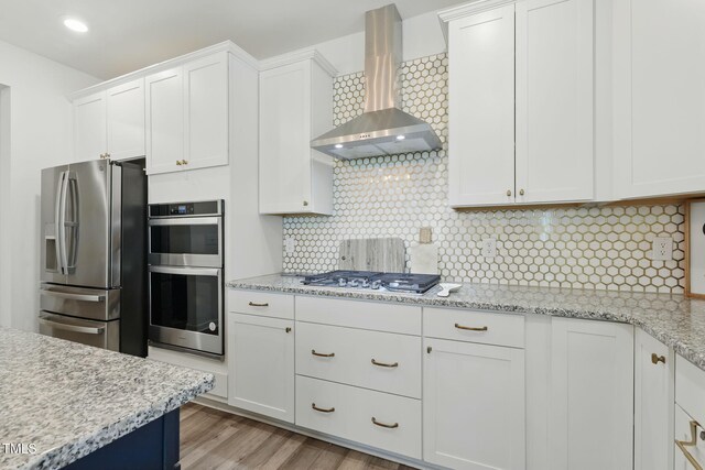 187 Harpers Landing Rd, Garner, NC 27529 - kitchen with wall chimney exhaust hood, appliances with stainless steel finishes, white cabinets, backsplash, and light wood-type flooring