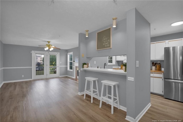 216 Waterdown Dr Unit 8, Fayetteville, NC 28314 - kitchen featuring freestanding refrigerator, a kitchen bar, light wood-type flooring, and white cabinets