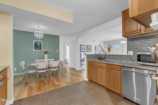 4009 Olde Coach Rd, Durham, NC 27707 - kitchen with appliances with stainless steel finishes, a sink, tasteful backsplash, dark tile patterned floors, and a peninsula
