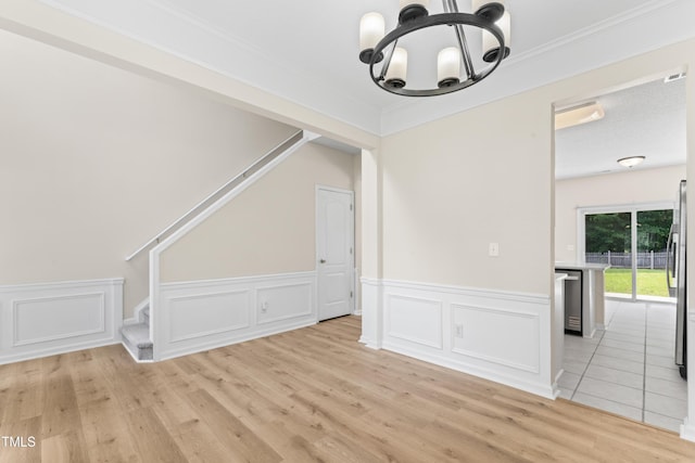 107 Woolard Way, Apex, NC 27502 - unfurnished dining area with stairway, a chandelier, light wood-type flooring, a wainscoted wall, and crown molding