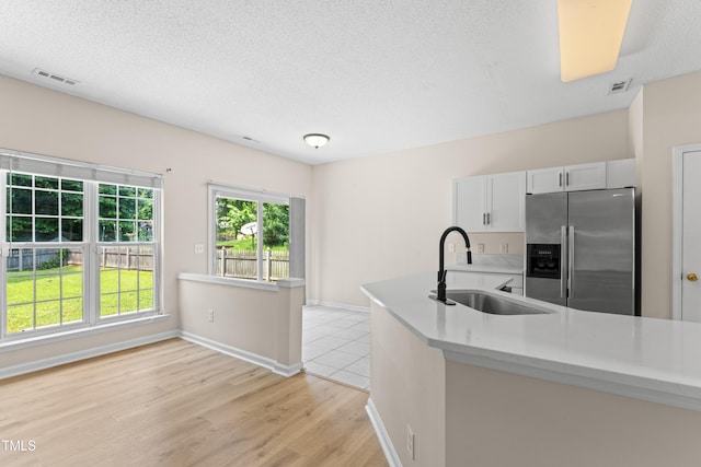 107 Woolard Way, Apex, NC 27502 - kitchen featuring stainless steel refrigerator with ice dispenser, a sink, light countertops, light wood finished floors, and a textured ceiling