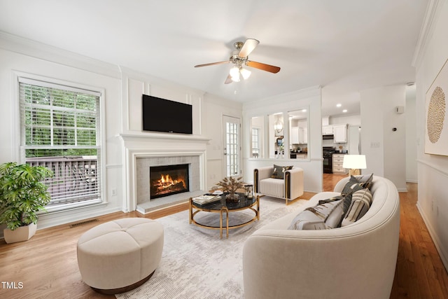 111 Catherwood Pl, Cary, NC 27518 - living room featuring healthy amount of natural light, a ceiling fan, a fireplace, light wood-style floors, and ornamental molding