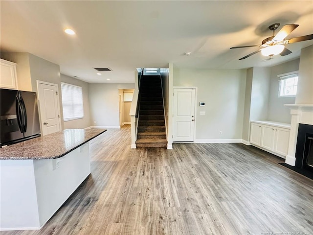 4179 Overhills Rd, Spring Lake, NC 28390 - kitchen with black fridge with ice dispenser, open floor plan, stone counters, white cabinets, and a fireplace with flush hearth