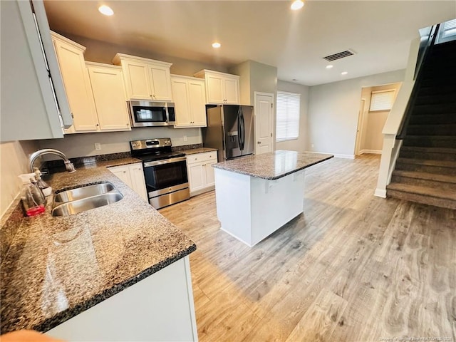 4179 Overhills Rd, Spring Lake, NC 28390 - kitchen featuring appliances with stainless steel finishes, a sink, a kitchen island, white cabinetry, and light wood-style floors