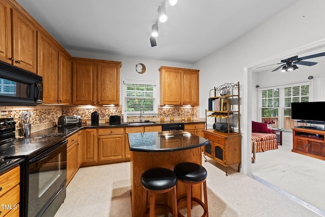 2313 Filigree Ct, Raleigh, NC 27614 - kitchen with black appliances, a sink, a center island, a kitchen breakfast bar, and tasteful backsplash