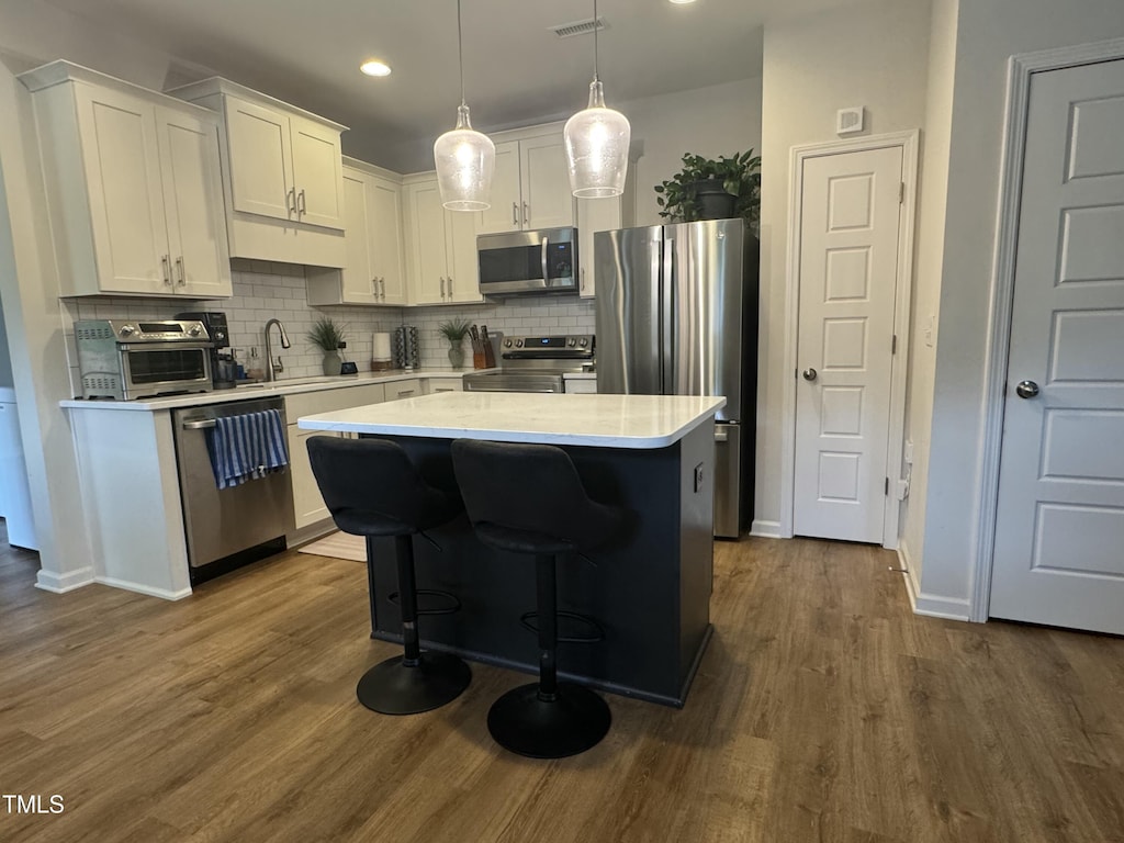 647 N Hardee St, Durham, NC 27703 - kitchen with stainless steel appliances, white cabinetry, light countertops, decorative backsplash, and a kitchen island