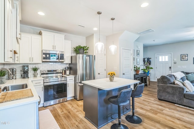 647 N Hardee St, Durham, NC 27703 - kitchen with appliances with stainless steel finishes, a sink, open floor plan, a breakfast bar, and a kitchen island