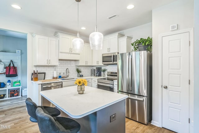 647 N Hardee St, Durham, NC 27703 - kitchen with appliances with stainless steel finishes, a sink, light countertops, a center island, and backsplash