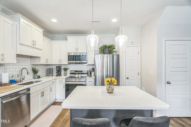647 N Hardee St, Durham, NC 27703 - kitchen with stainless steel appliances, a sink, light wood-style floors, decorative backsplash, and a kitchen bar