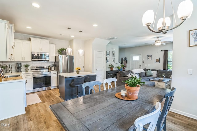 647 N Hardee St, Durham, NC 27703 - dining room with light wood-type flooring, a ceiling fan, a chandelier, recessed lighting, and baseboards