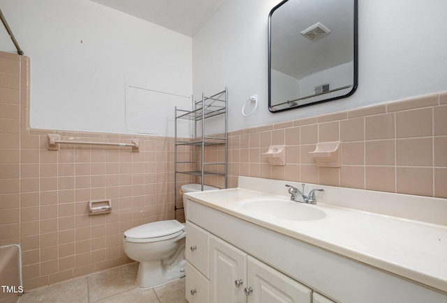 134 Chateau Rd, Durham, NC 27704 - bathroom with tile walls, toilet, tile patterned floors, vanity, and a wainscoted wall