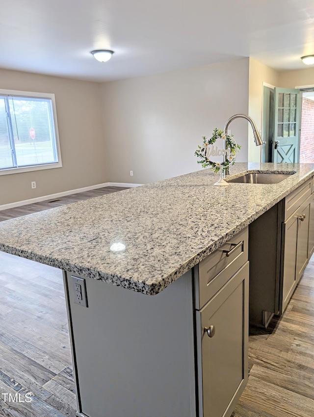 1602 Fairground Rd, Dunn, NC 28334 - kitchen with a sink, light wood finished floors, light stone countertops, a kitchen island with sink, and baseboards