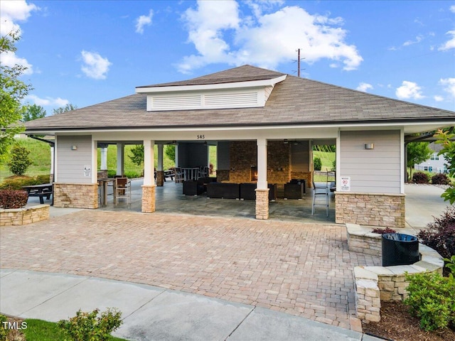 1704 Fawn Chase Ct, Wake Forest, NC 27587 - view of front of home with outdoor lounge area, a patio area, exterior kitchen, roof with shingles, and stone siding